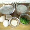 Nhặt sạch hành lá, thái nhỏ. Đập 3 quả trứng gà cho vào tô, khuấy tan trứng. Rây nửa chén bột mì vào 300ml sữa tươi không đường, khuấy cho quyện đều. Sau đó đổ chén sữa và bột vào tô trứng, khuấy cho quyện đều.